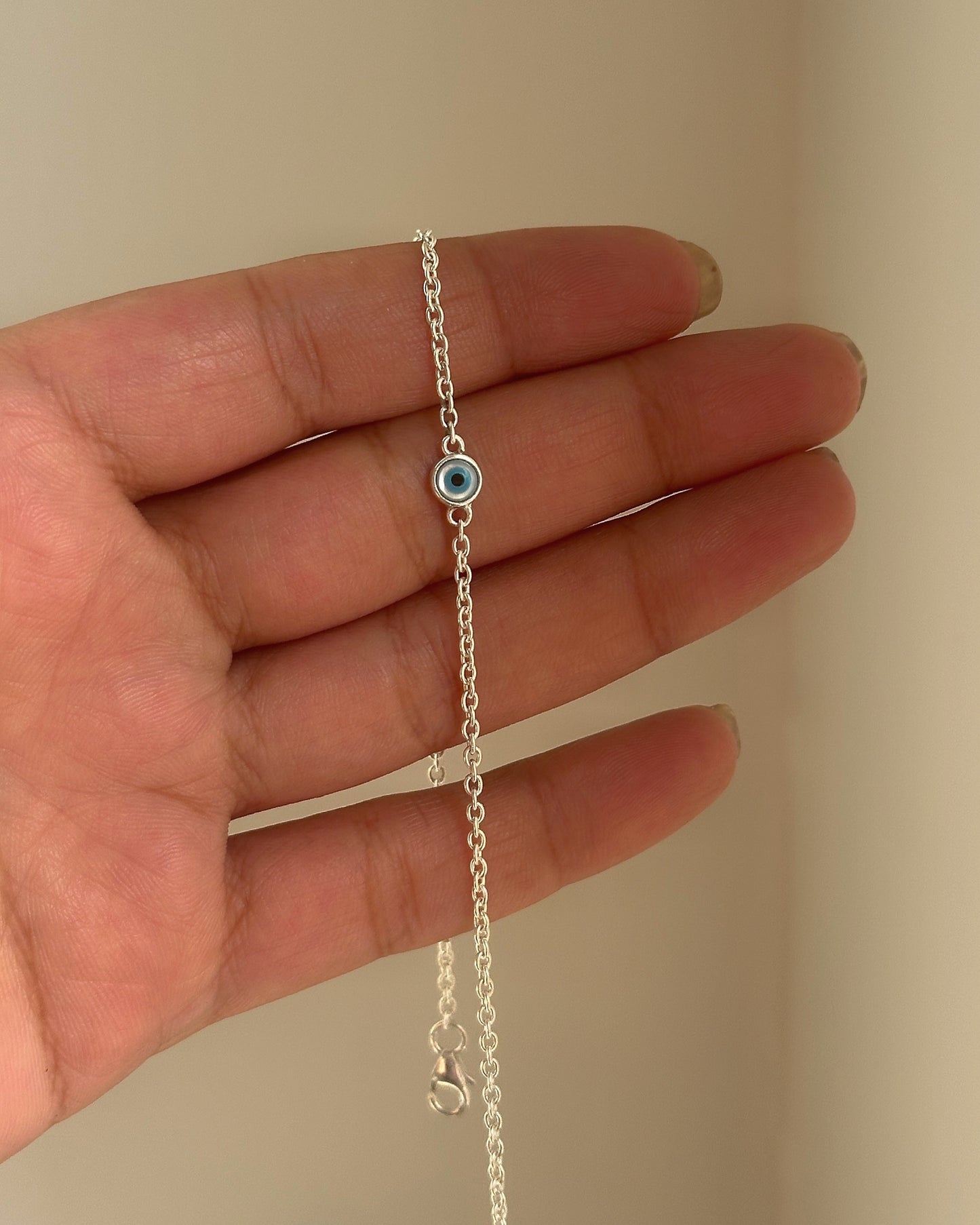 minimal nazar anklet close-up — small blue evil eye charm detail