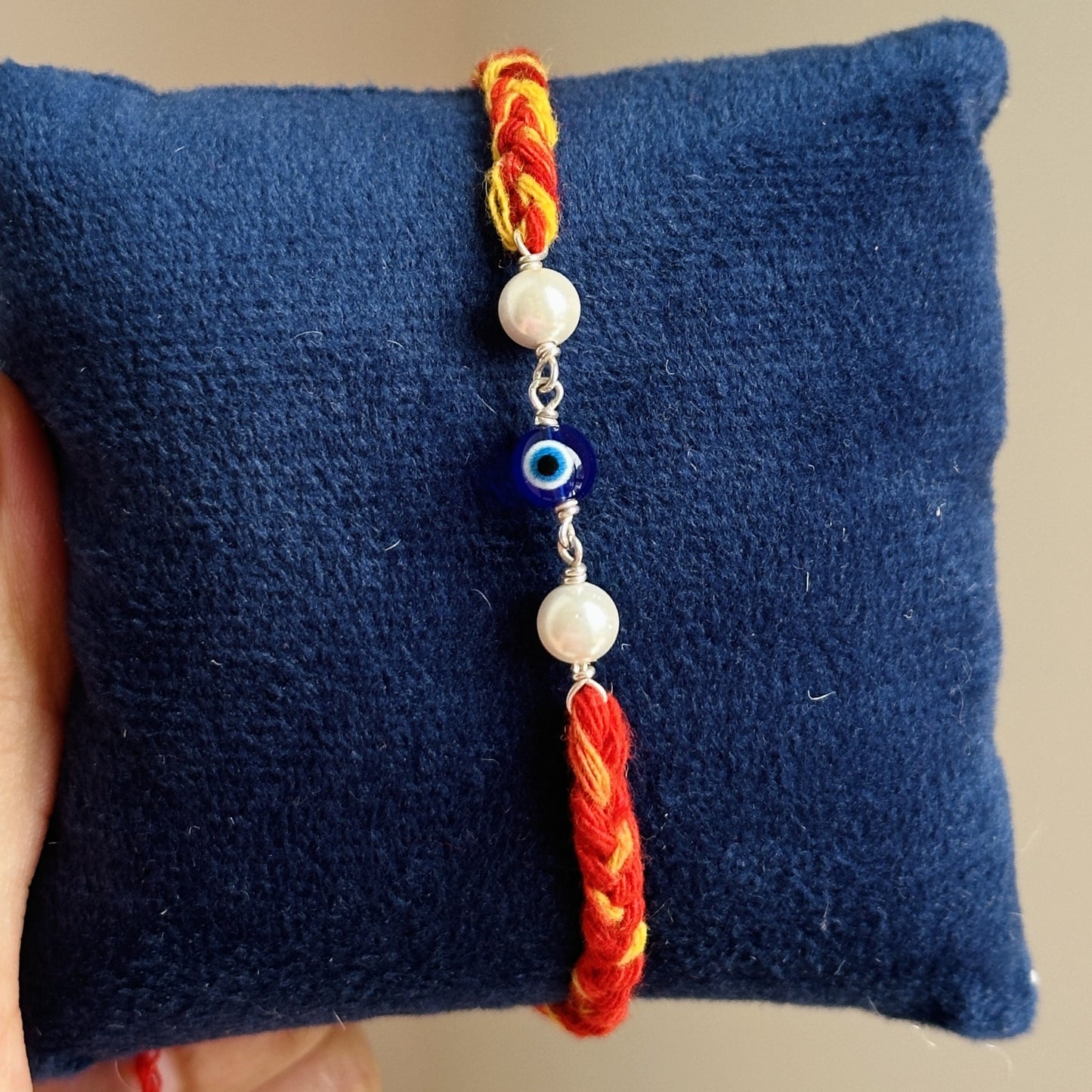 pearl evil eye rakhi close-up — evil eye charm with white pearl beads