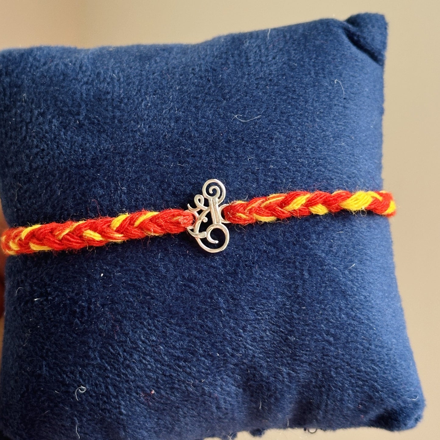 shri ganesh rakhi close-up — silver shri and ganesha motif detail