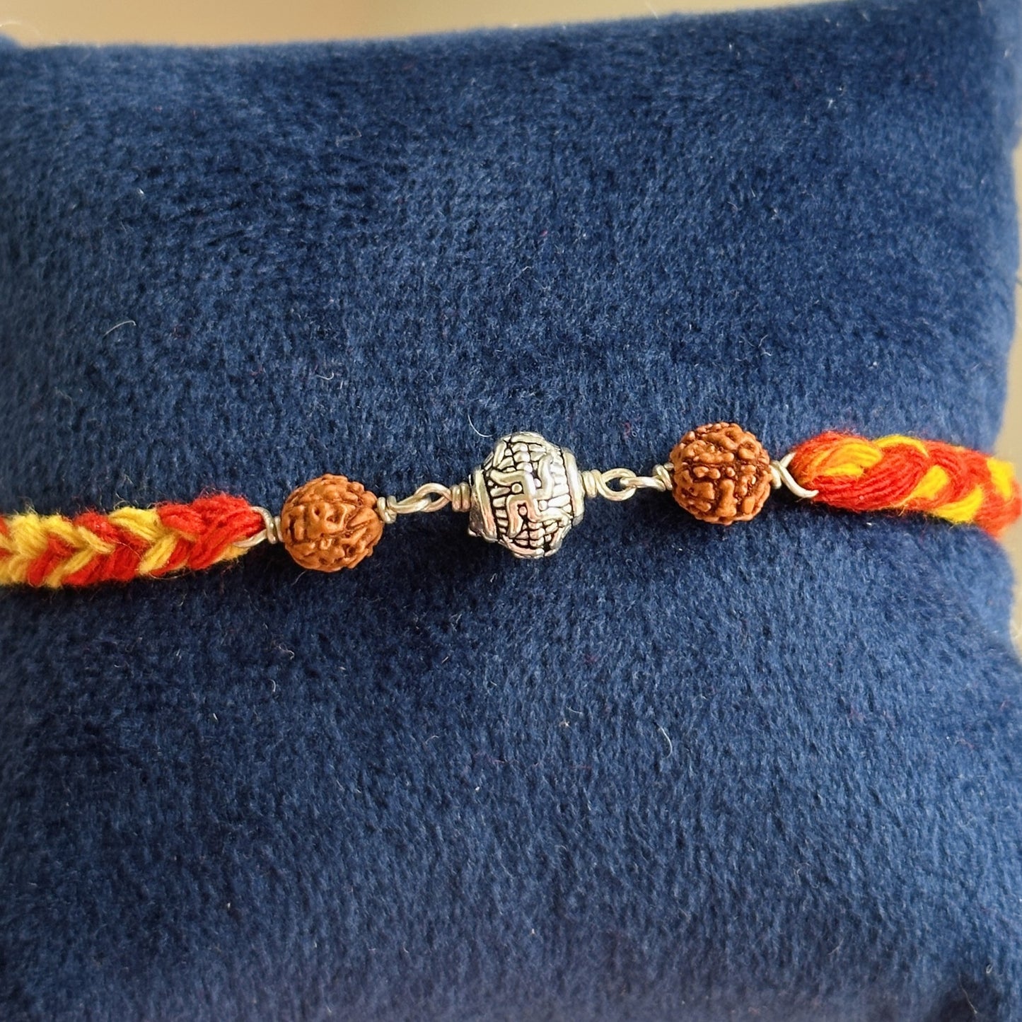 divine swastik rudraksha rakhi close-up — swastik and rudraksha bead detail