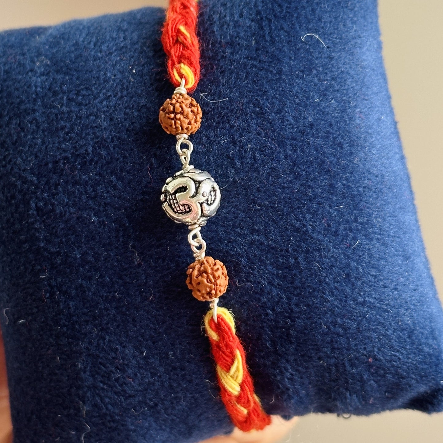 om blessing rudraksha rakhi worn on wrist — silver om and rudraksha rakhi
