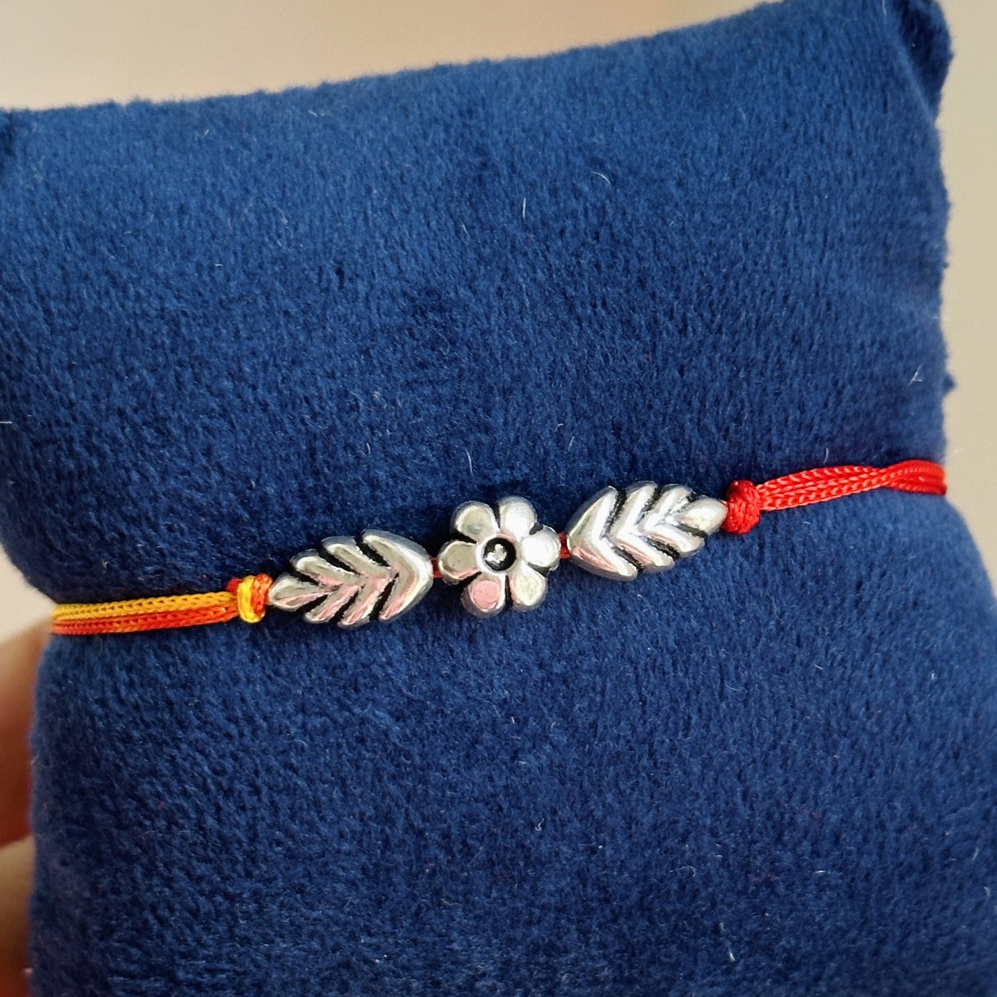 leaf and bloom rakhi close-up — silver flower and leaf detail