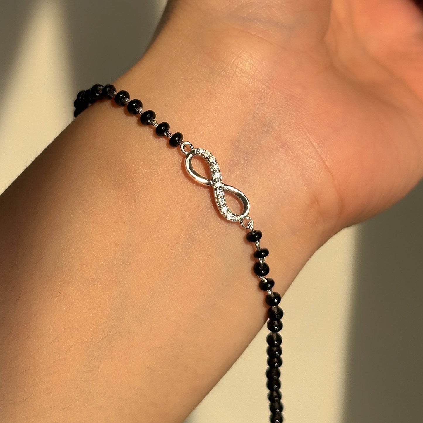 infinity mangalsutra bracelet close-up — infinity motif and black beads